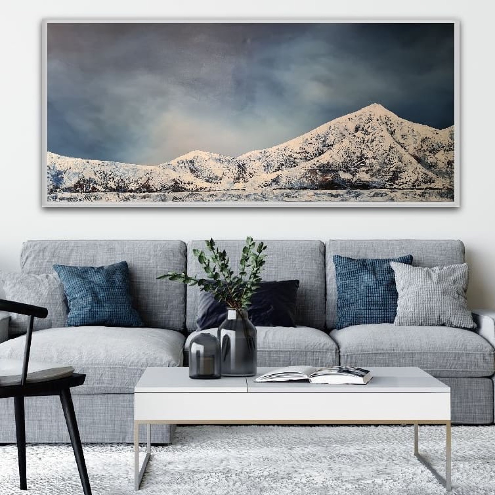 A panoramic mountain painting by Anni Thorn above a sofa in a contemporary living room